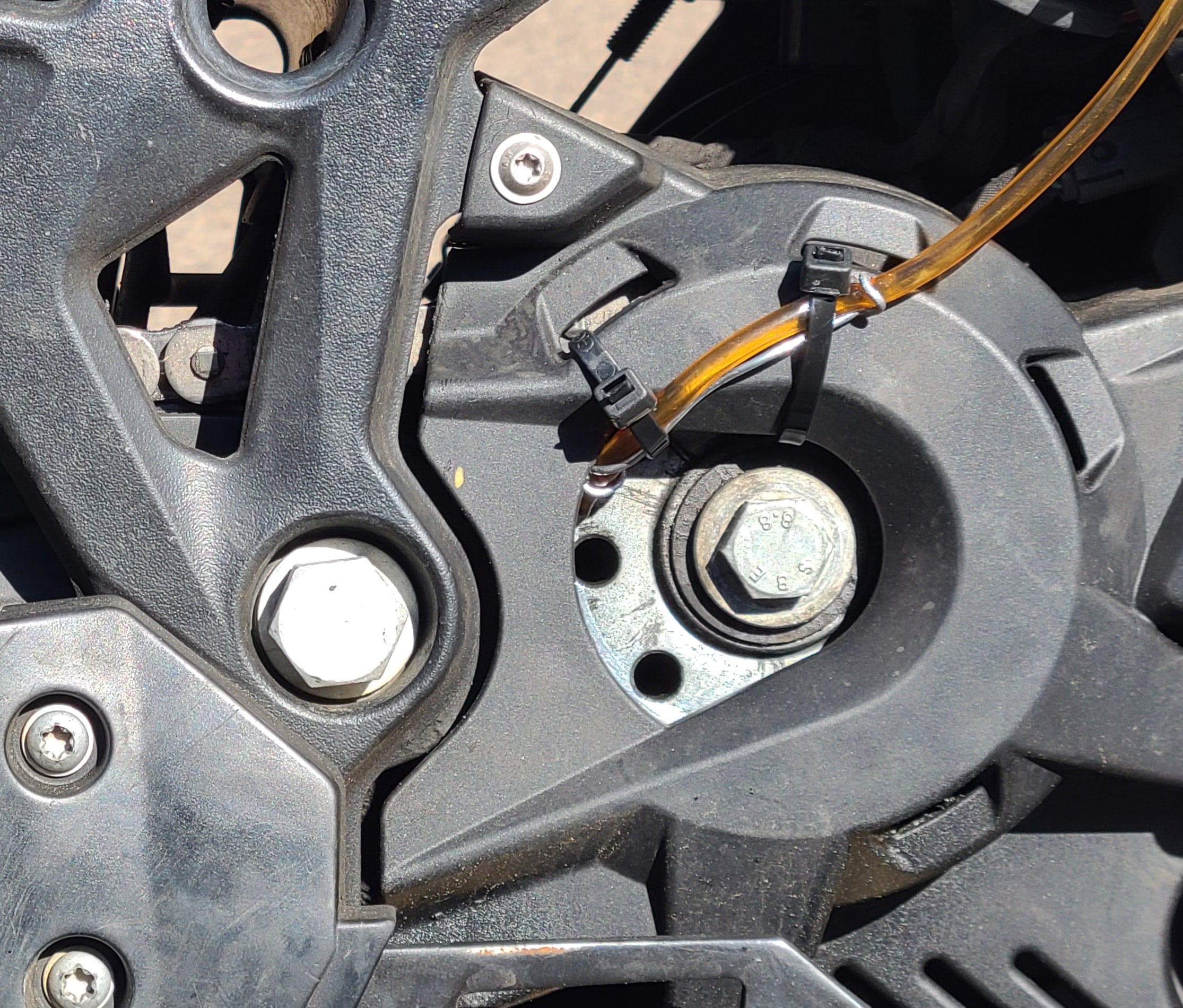 view of a hose entering plastic cover of a motorcycle countersprocket