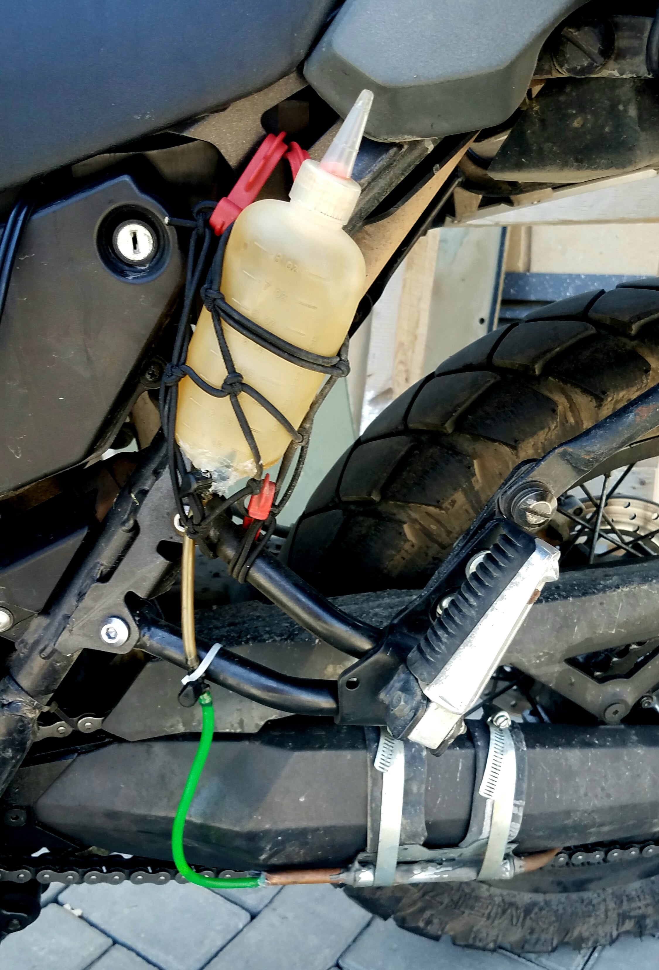 plastic bottle with hoses on the side of a motorcycle 